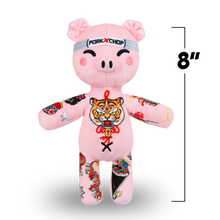 Load image into Gallery viewer, Pink plush toy pig with tattoos and a tiger design, wearing a gray headband, on a white background with a 'Pork Chop' brand label.